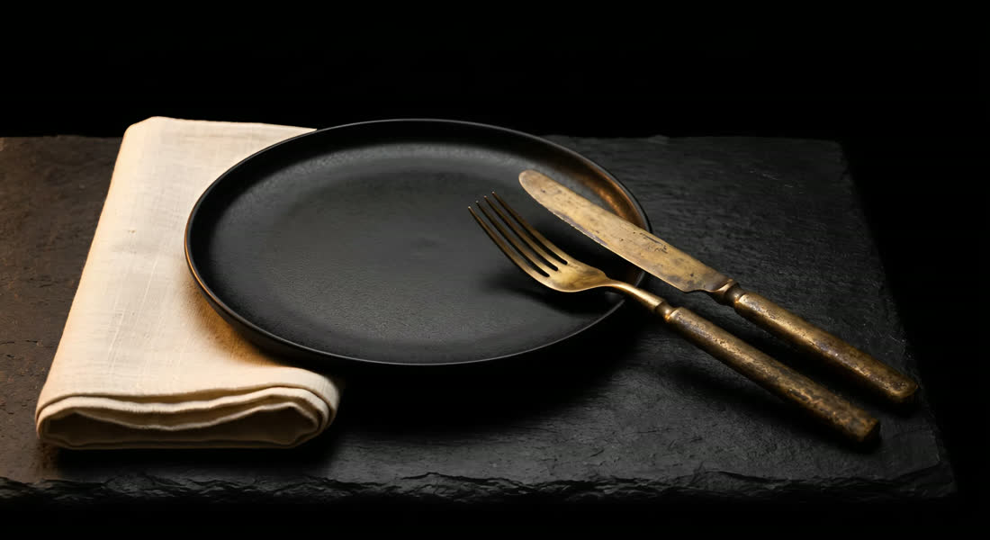 A place setting: black plate, aged brass, linen